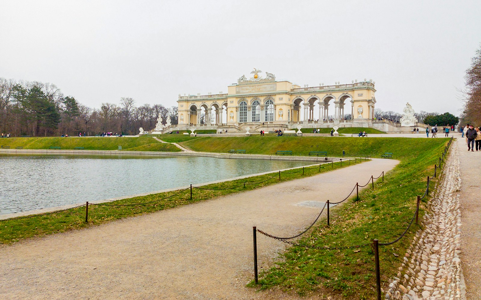 Gloriette at Schönbrunn Palace with reflecting pond and walking path, Vienna, Austria.