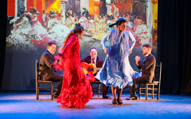 Flamenco dancers performing at Teatro Flamenco Sevilla with musicians in the background.