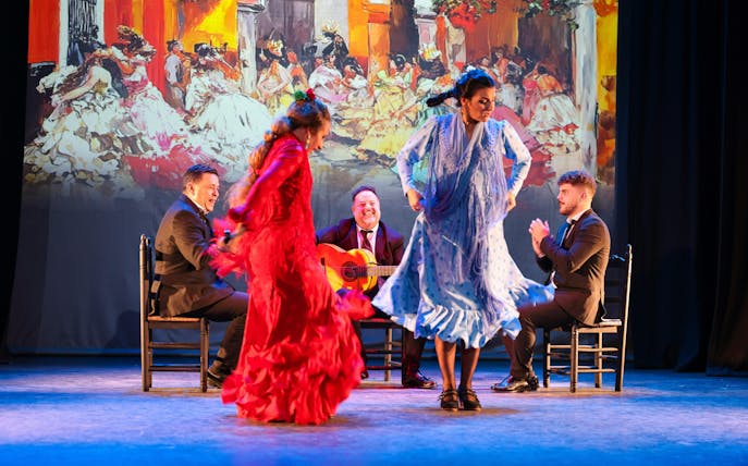 Flamenco dancers performing at Teatro Flamenco Sevilla with musicians in the background.