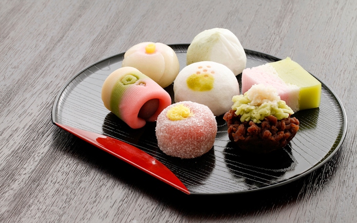 Japanese sweets assortment on a black plate for a private tea ceremony experience.