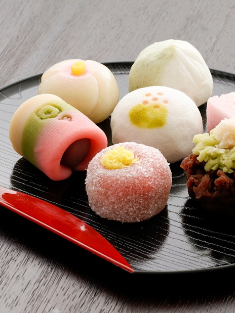 Japanese sweets assortment on a black plate for a private tea ceremony experience.