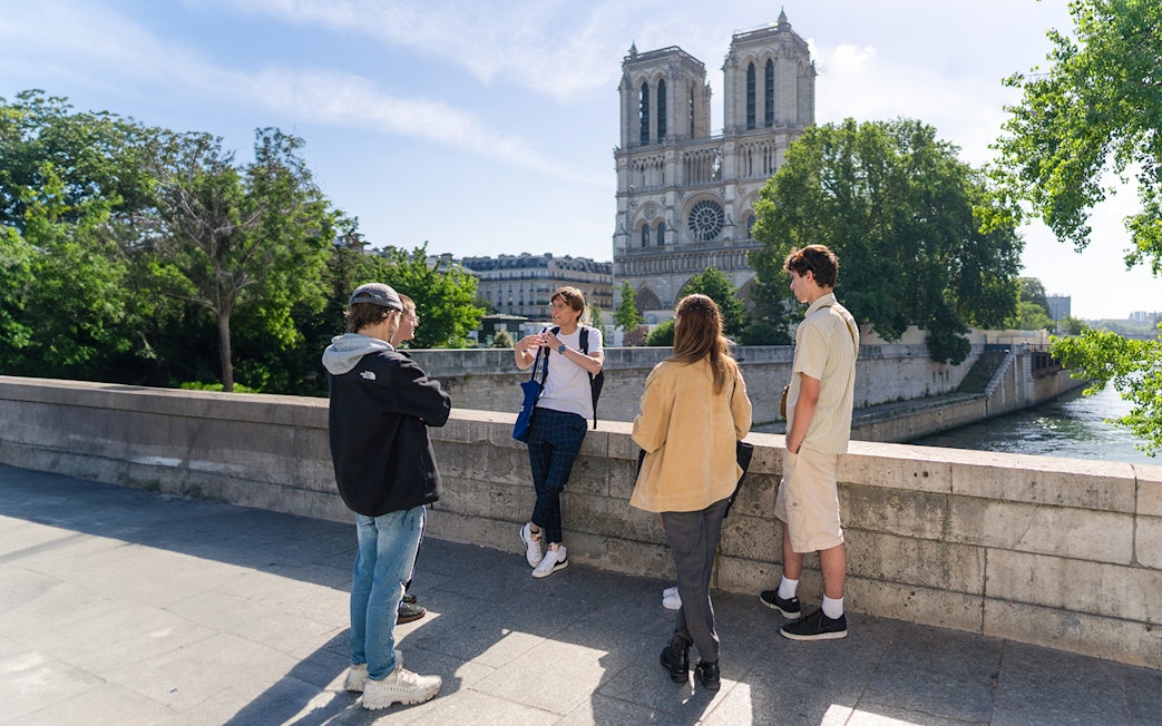 Group of tourists listening to a guide near Notre Dame Cathedral on Notre Dame Island, Paris.