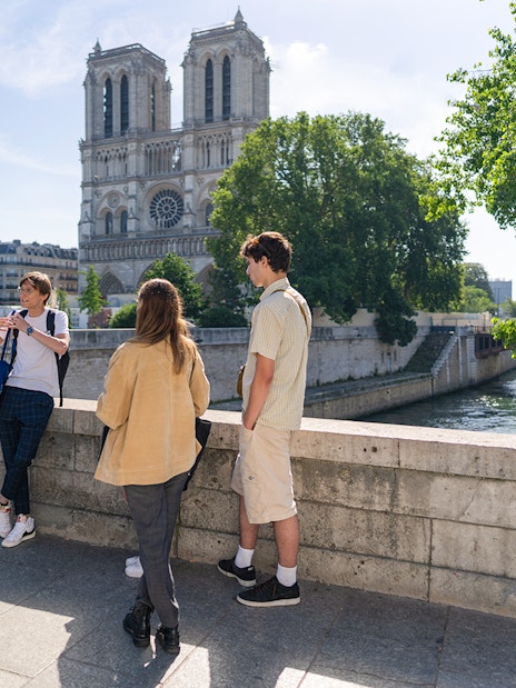 Group of tourists listening to a guide near Notre Dame Cathedral on Notre Dame Island, Paris.