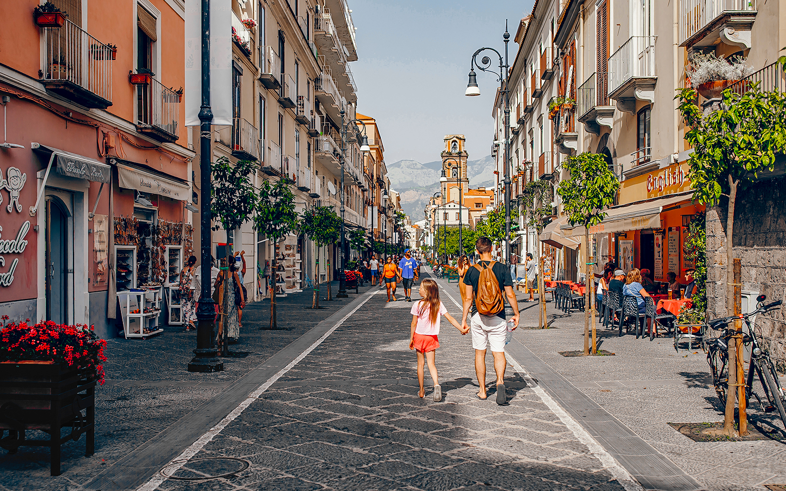 Pedestrians walking along Corso Italia in Sorrento, Italy, with shops and cafes lining the street.