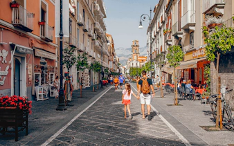 Pedestrians walking along Corso Italia in Sorrento, Italy, with shops and cafes lining the street.