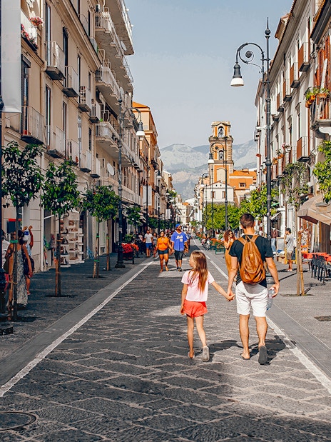 Pedestrians walking along Corso Italia in Sorrento, Italy, with shops and cafes lining the street.