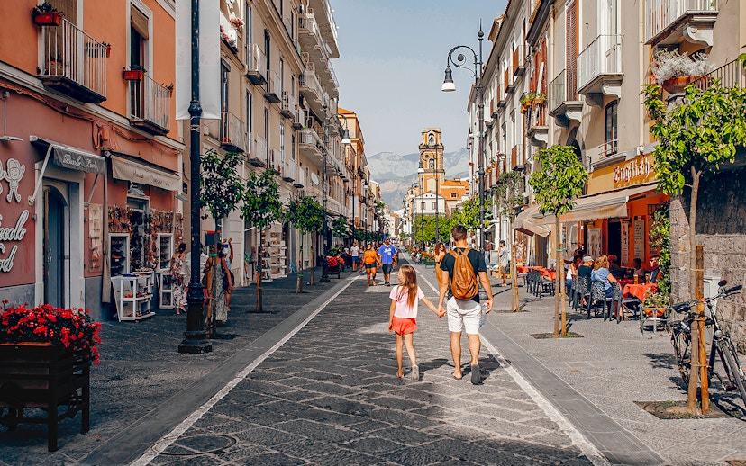 Pedestrians walking along Corso Italia in Sorrento, Italy, with shops and cafes lining the street.