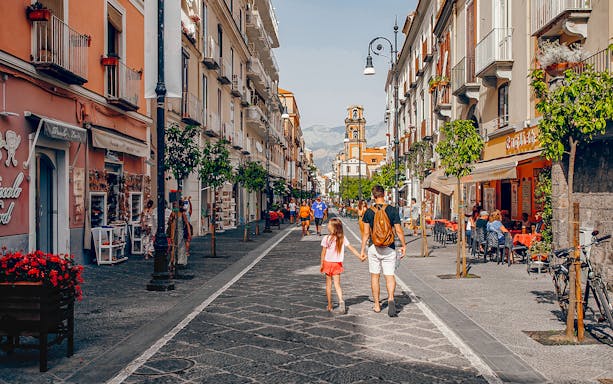 Pedestrians walking along Corso Italia in Sorrento, Italy, with shops and cafes lining the street.