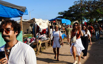 Local market scene in Diani Beach, Kenya, with people walking past stalls.