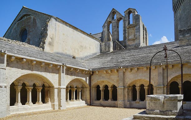 Montmajour Abbey cloister with stone arches and central well in Provence, France.