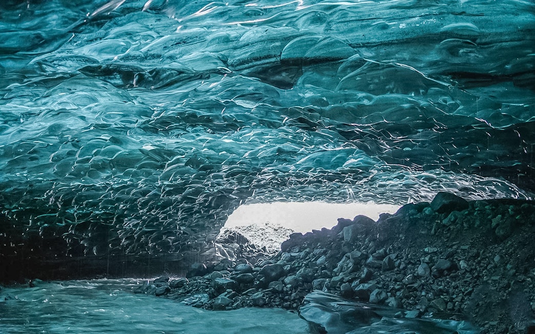 Crystal Ice Cave interior with textured blue ice ceiling and rocky floor.