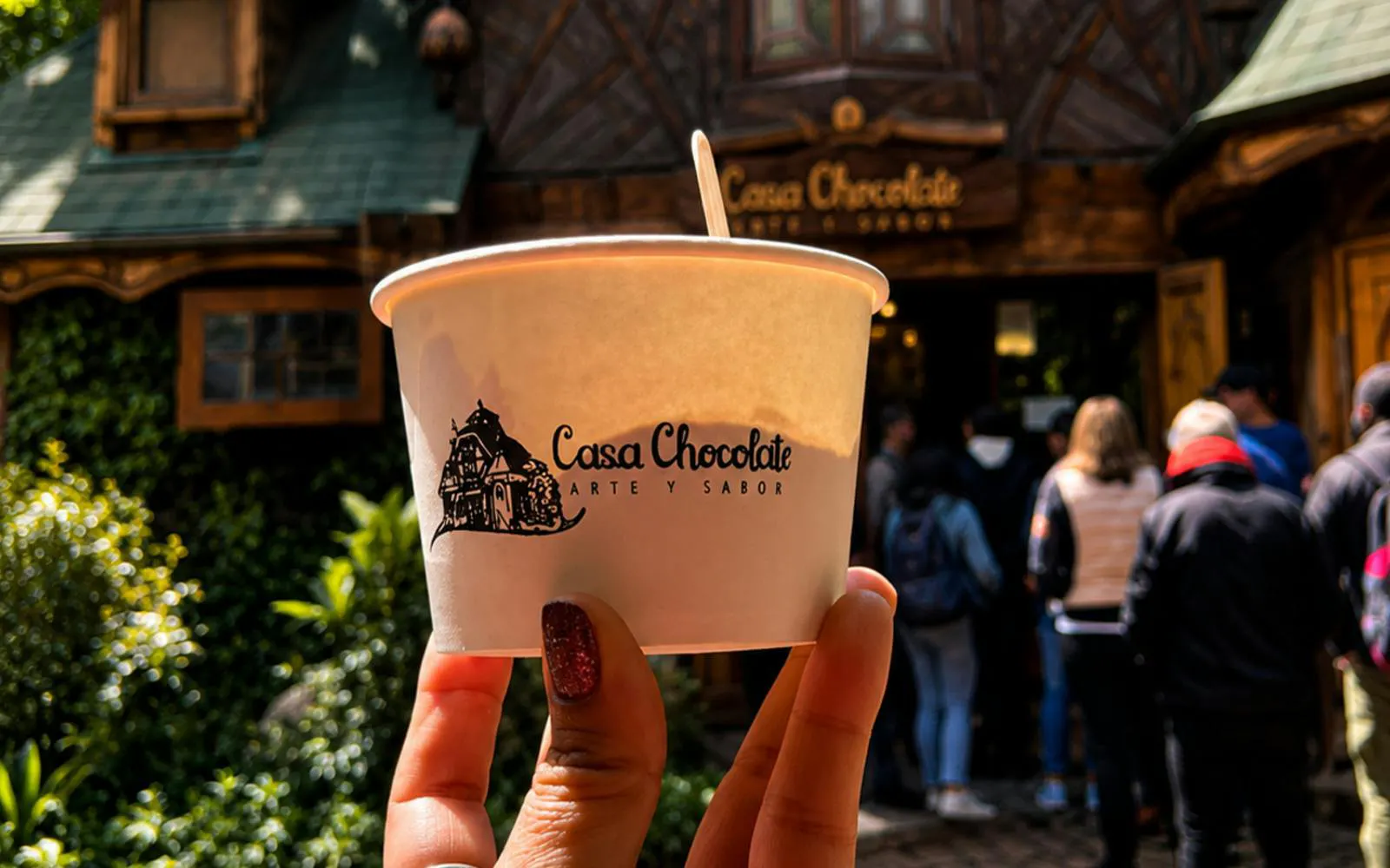 Tourists gather outside Casa Chocolate, holding a branded cup.