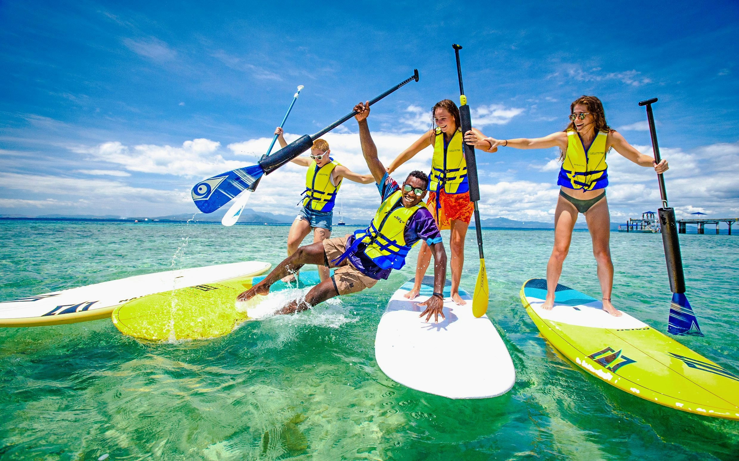 Friends paddle surfing at Malamala Beach Club, Fiji.