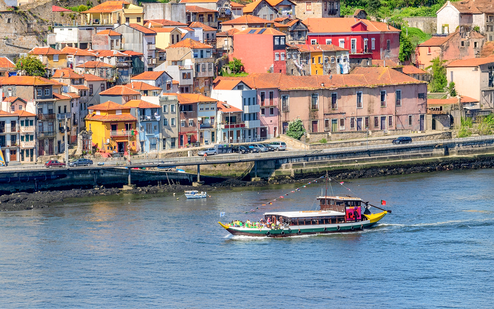 Boat cruising on Douro River with colorful Porto buildings in the background.