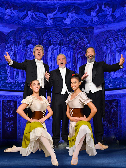 Opera singers and dancers performing in front of a blue-lit mural at night.