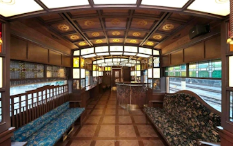 Luxurious interior of a Kyushu rail train with wooden decor and stained glass windows.