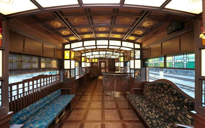 Luxurious interior of a Kyushu rail train with wooden decor and stained glass windows.