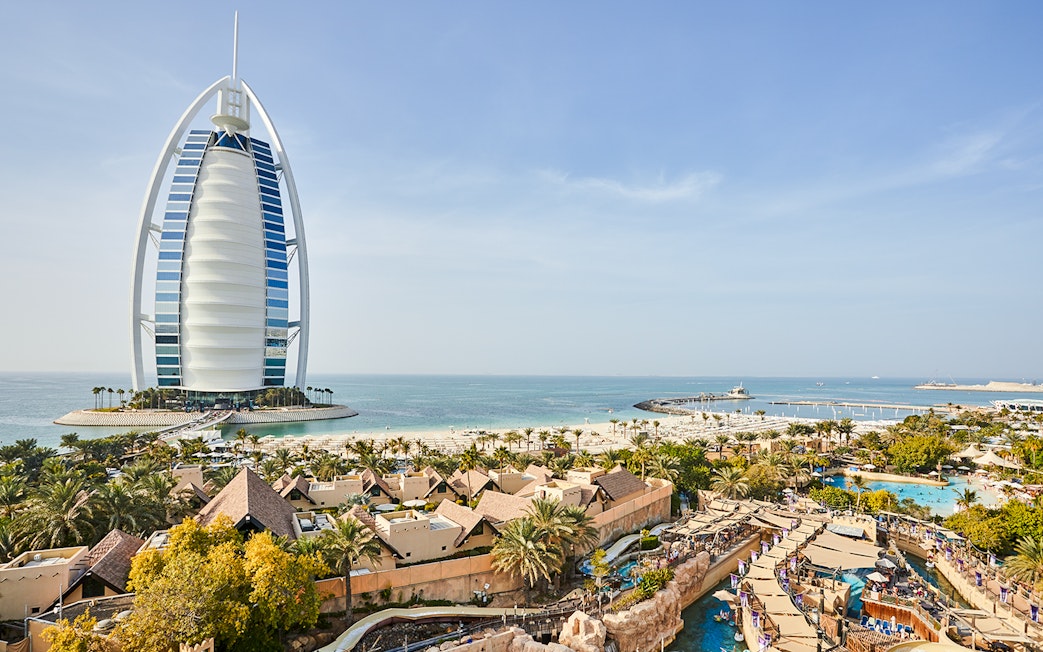 Family enjoying water slide at Wild Wadi Water Park, Dubai, with Burj Al Arab in background.