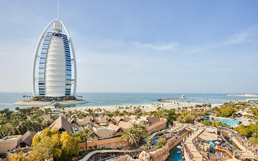 Family enjoying water slide at Wild Wadi Water Park, Dubai, with Burj Al Arab in background.