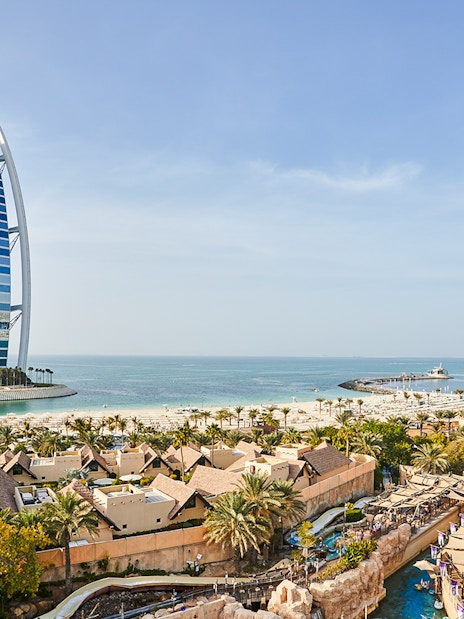 Family enjoying water slide at Wild Wadi Water Park, Dubai, with Burj Al Arab in background.