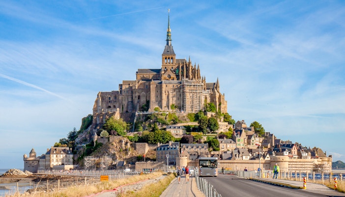 Mont Saint Michel abbey view with tourists exploring the historic island on a day trip.