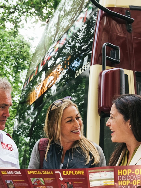 Tourists with a guide in front of a Los Angeles hop-on hop-off bus, holding a map.