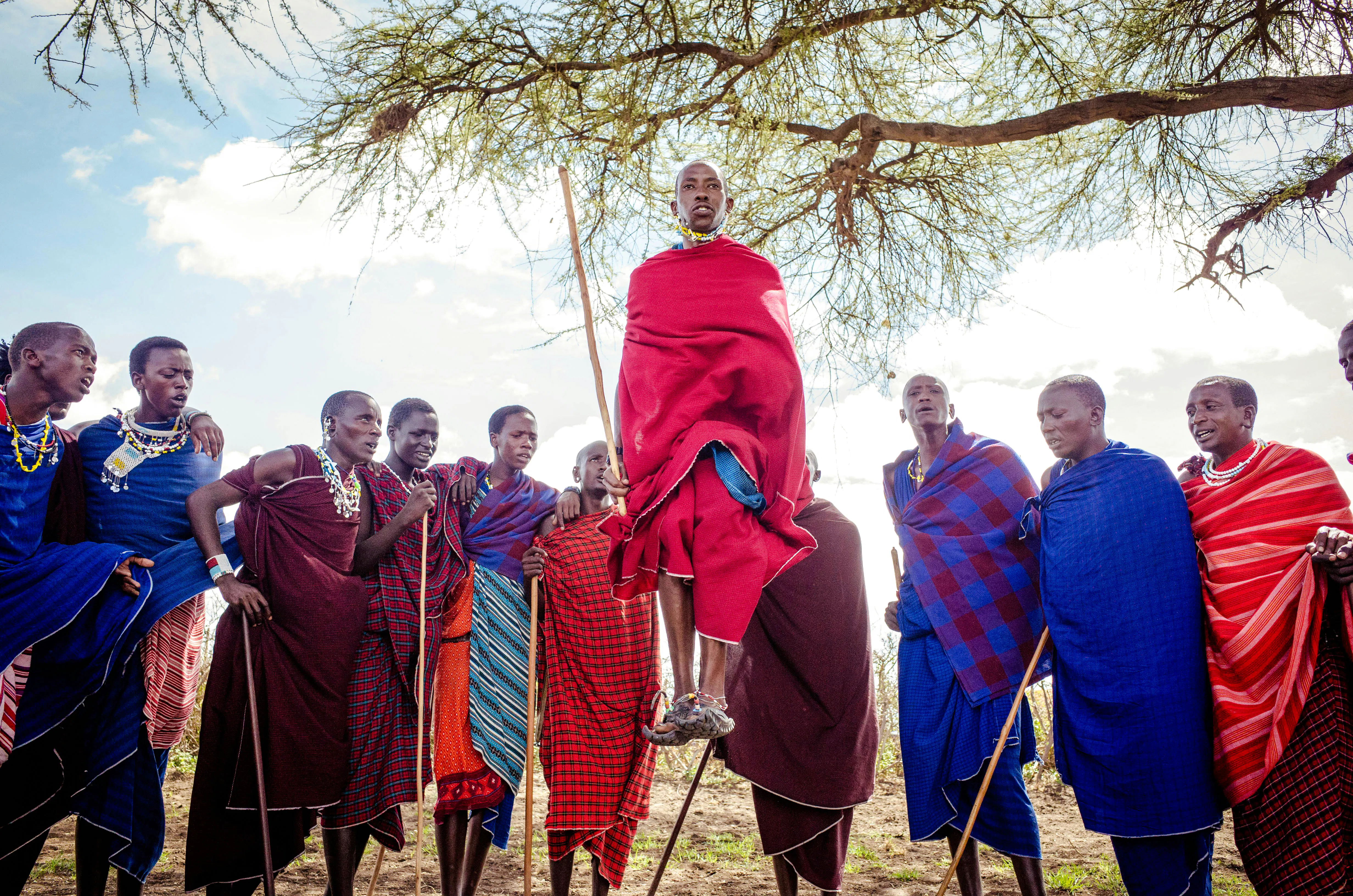 Maasai villagers performing traditional dance in Zanzibar, wearing colorful attire.