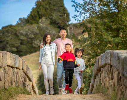 Family walking on a stone bridge at Hobbiton Movie Set, New Zealand.