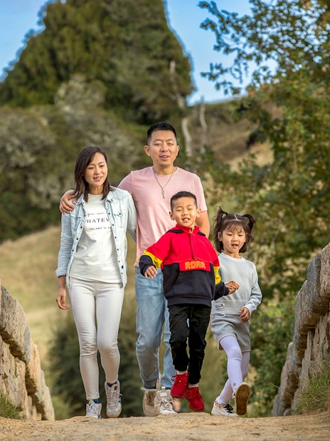 Family walking on a stone bridge at Hobbiton Movie Set, New Zealand.