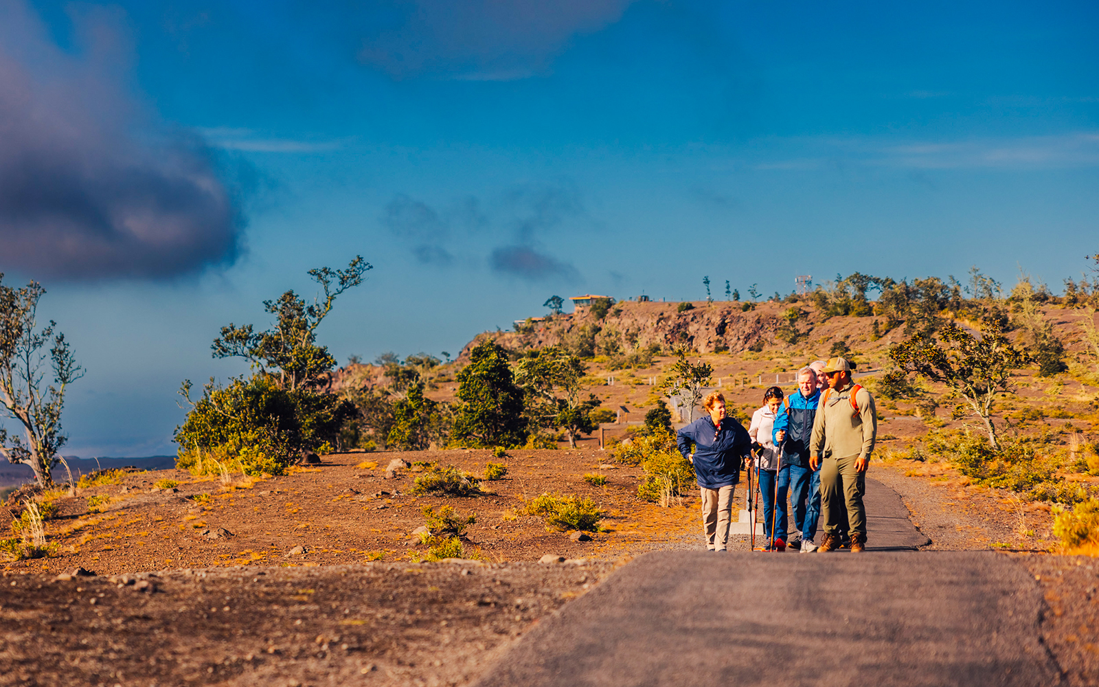 Guests hiking on a volcanic trail in Hawaii with scenic views.