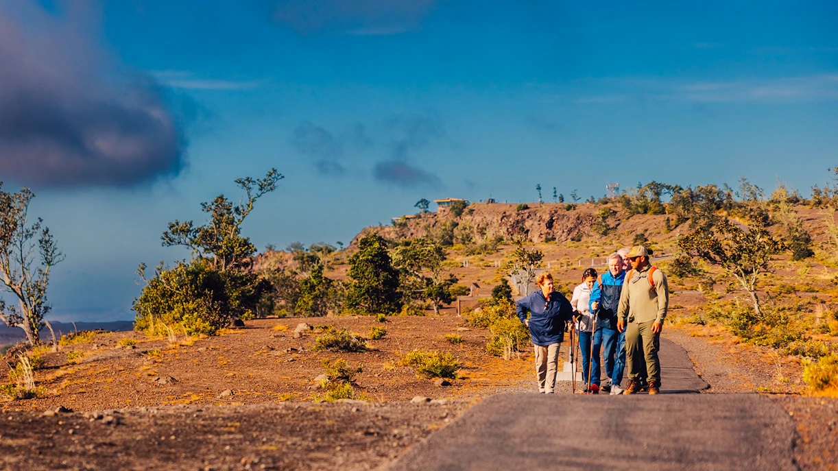Guests hiking on a volcanic trail in Hawaii with scenic views.