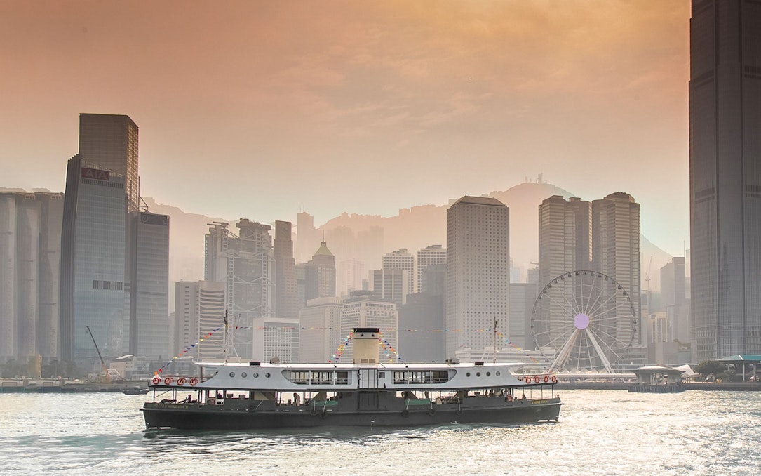 Star Ferry crossing Victoria Harbor with Hong Kong skyline in the background.