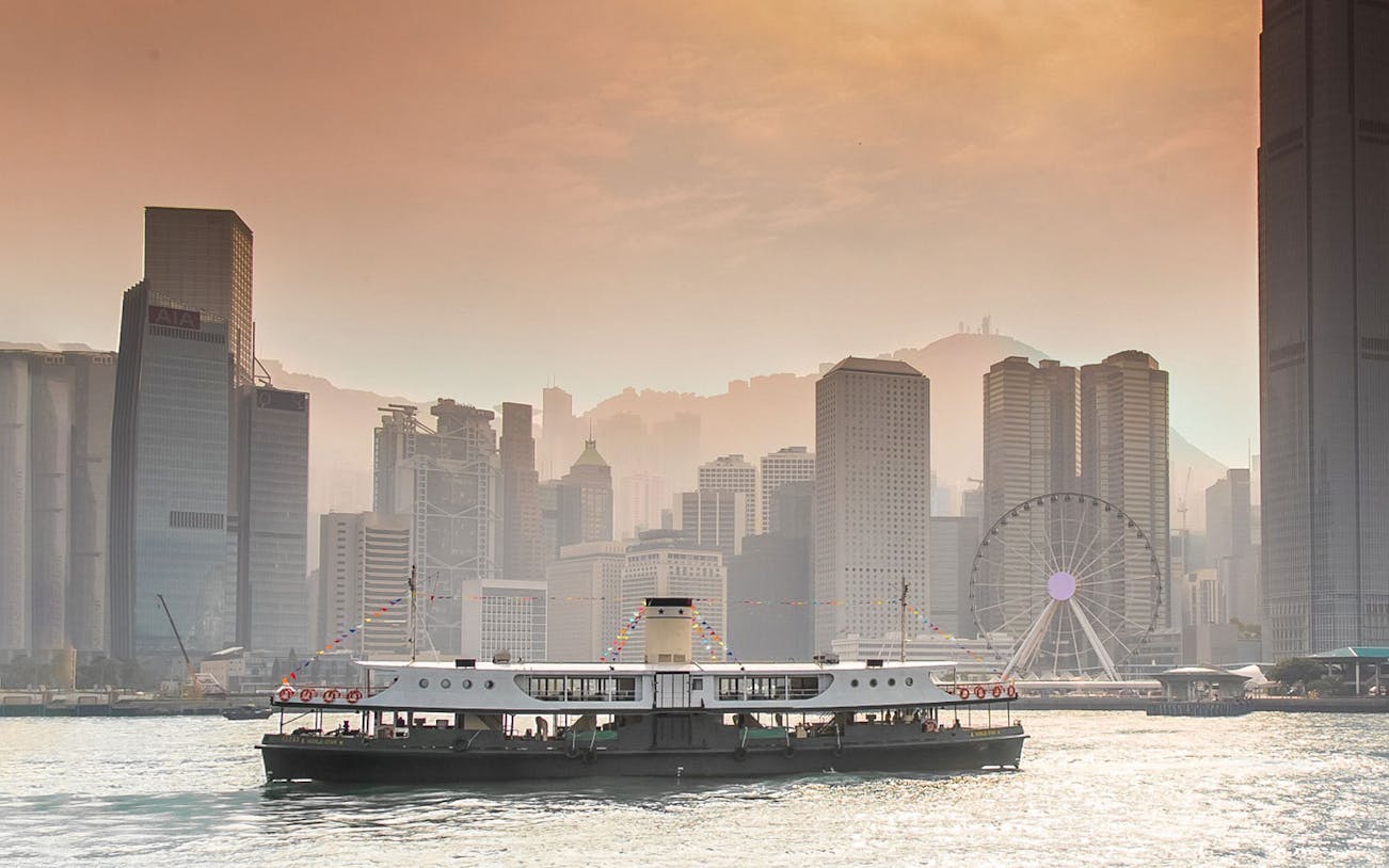 Star Ferry crossing Victoria Harbor with Hong Kong skyline in the background.