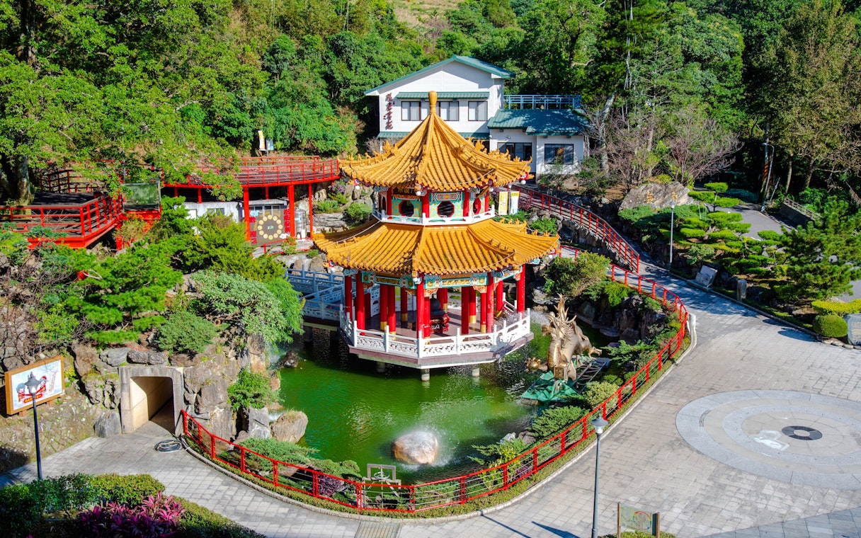 Pagoda and pond at Maokong Gondola station, Taipei, surrounded by lush greenery.