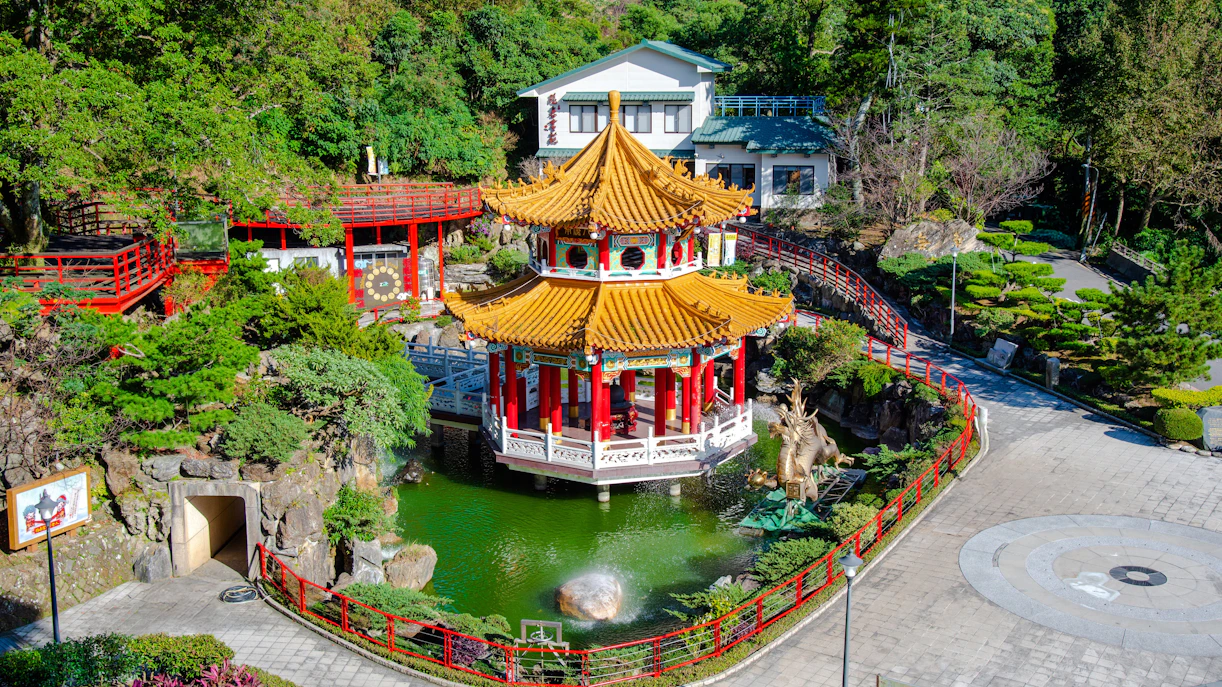 Pagoda and pond at Maokong Gondola station, Taipei, surrounded by lush greenery.