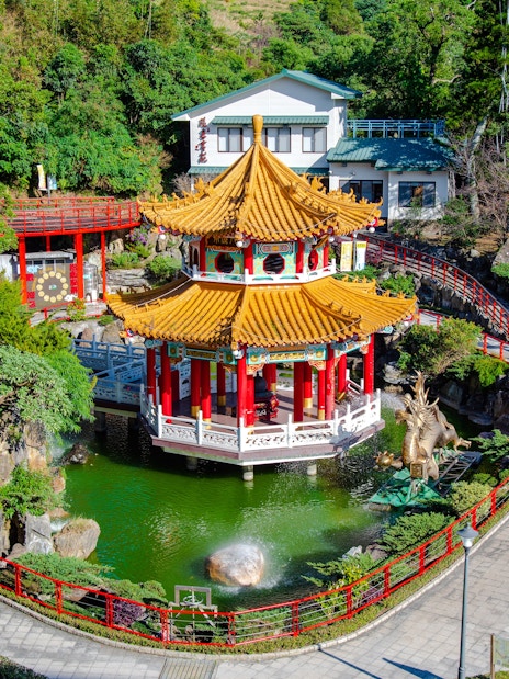 Pagoda and pond at Maokong Gondola station, Taipei, surrounded by lush greenery.