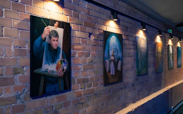 Paintings displayed on a brick wall at the Interactive DeJa Vu Museum in Berlin.