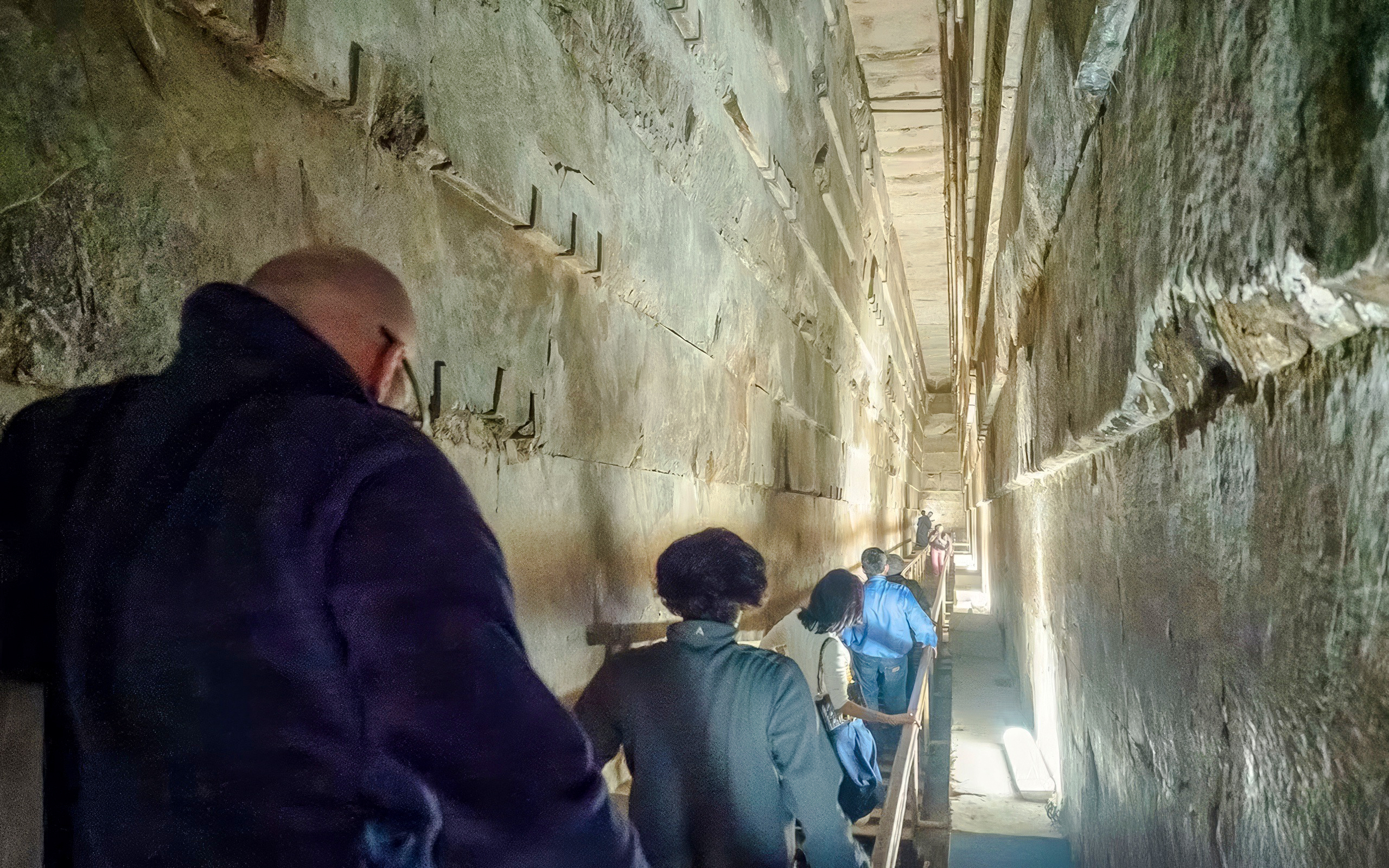 Tourists walking through a narrow passage inside the Great Pyramid of Khufu, Giza Necropolis.