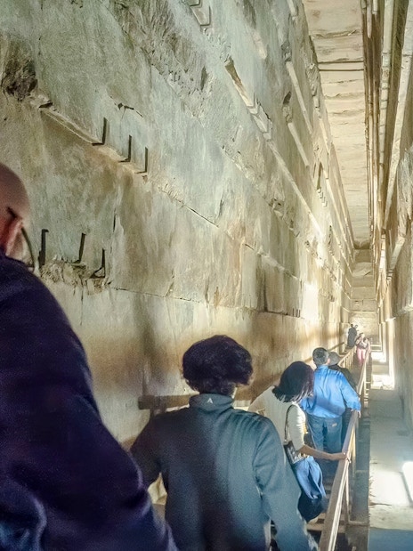 Tourists walking through a narrow passage inside the Great Pyramid of Khufu, Giza Necropolis.