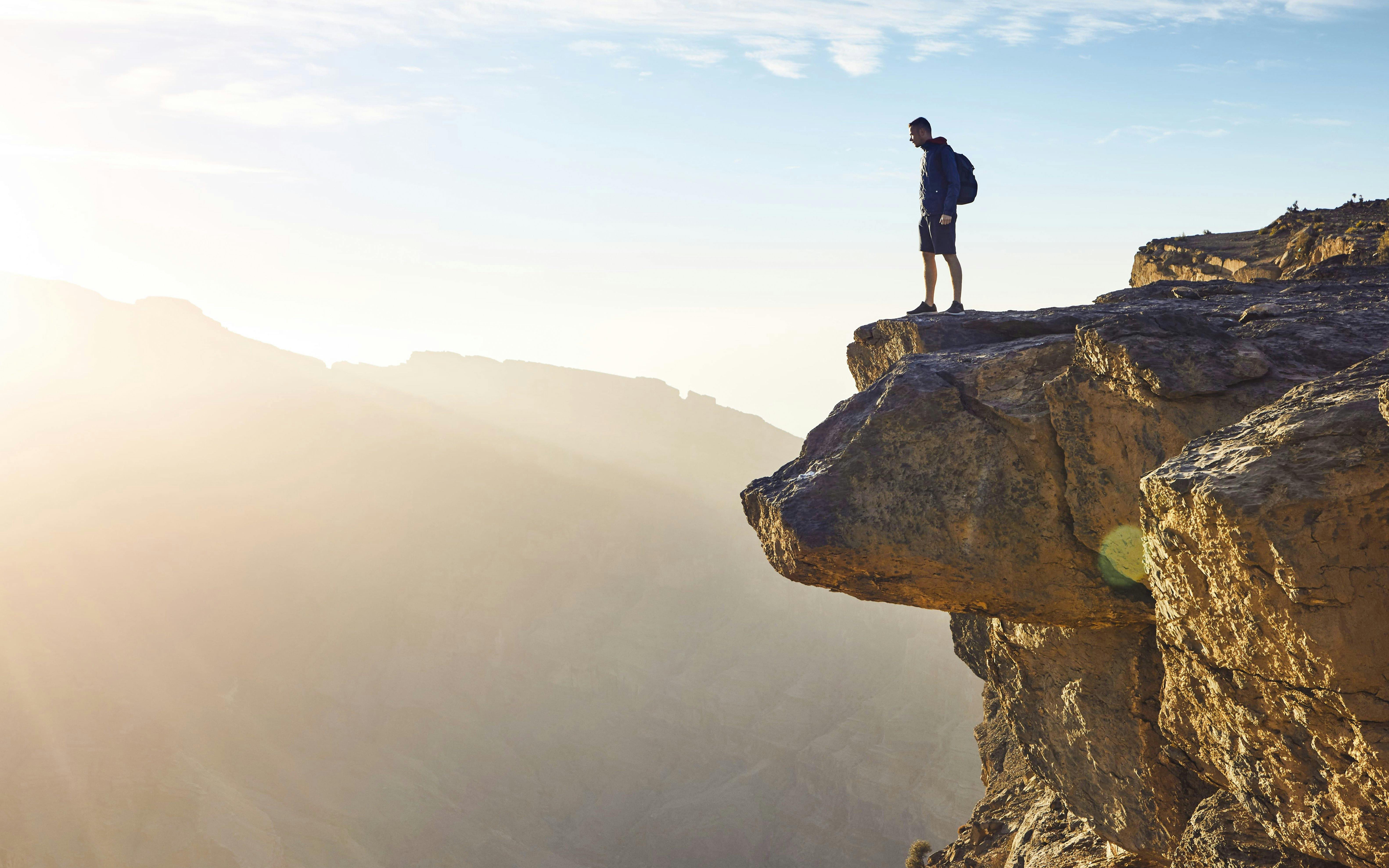 Visitor standing on cliff edge at Oman Grand Canyon.