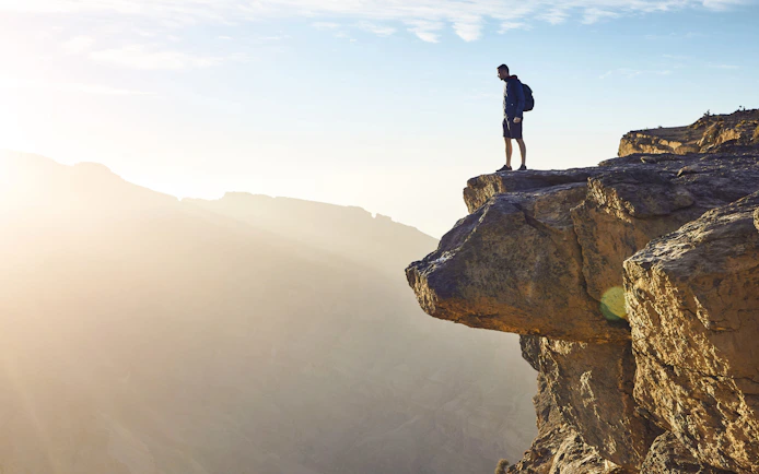 Visitor standing on cliff edge at Oman Grand Canyon.