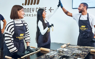 Participants enjoying a Chimney Cake workshop in Budapest, preparing dough with rolling pins.
