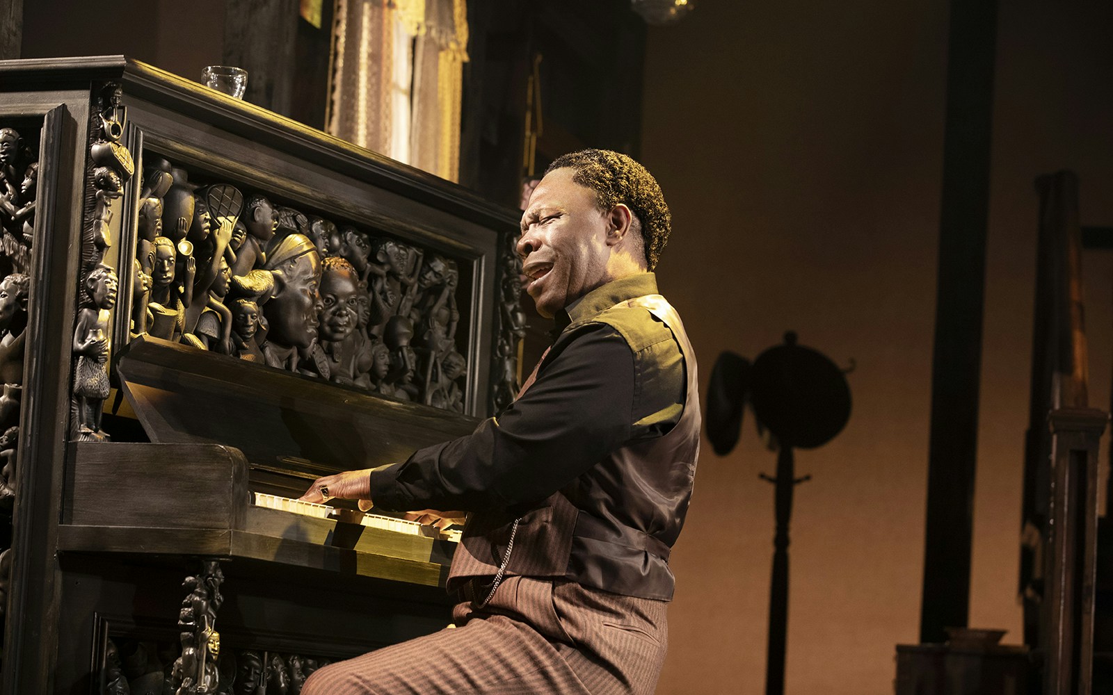 Man playing an intricately carved piano during a performance of "The Piano Lesson.