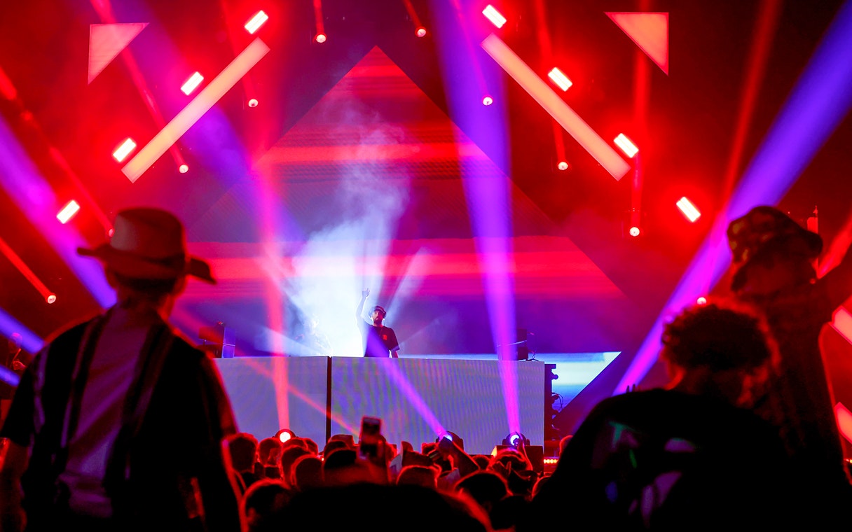 DJ performing at Emirates Dubai 7s Sunroom Hospitality event with vibrant lights.