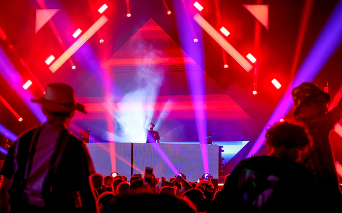DJ performing at Emirates Dubai 7s Sunroom Hospitality event with vibrant lights.