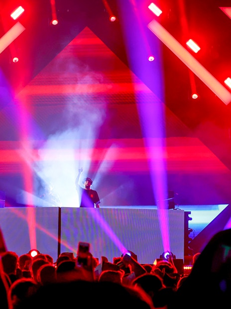 DJ performing at Emirates Dubai 7s Sunroom Hospitality event with vibrant lights.