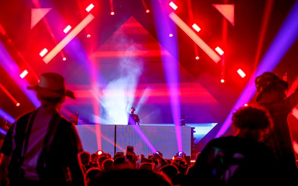 DJ performing at Emirates Dubai 7s Sunroom Hospitality event with vibrant lights.