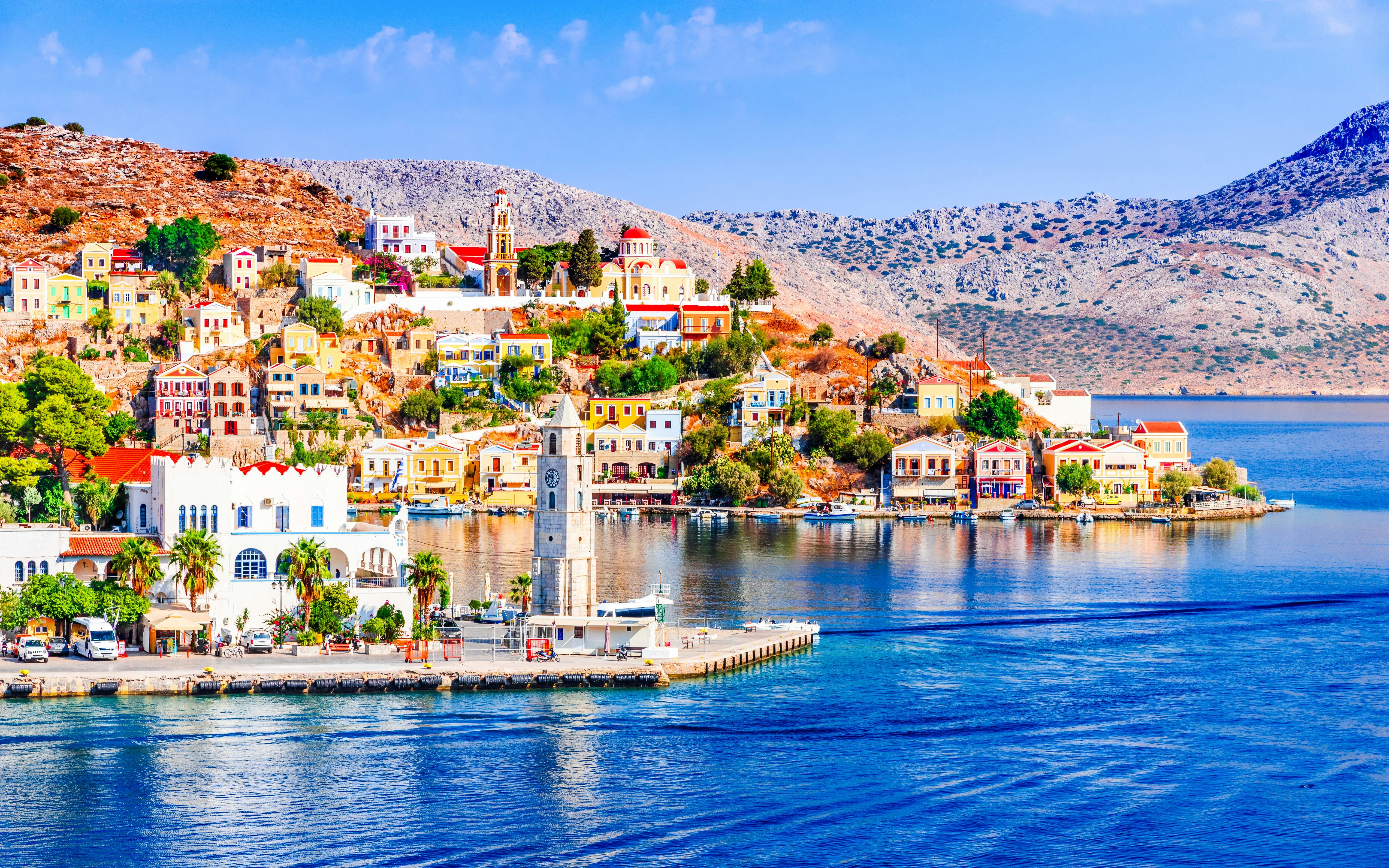 Symi Island Harbor with colorful buildings and clock tower during Rhodes cruise, Greece.