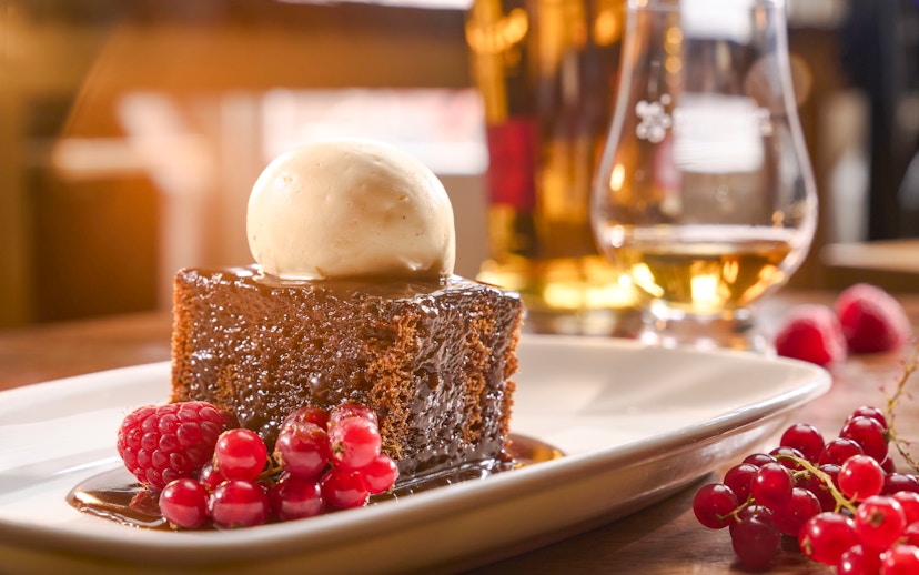 Sticky toffee pudding with ice cream and berries, paired with a glass of Scotch whisky.
