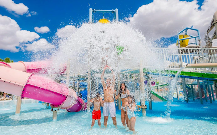 Family enjoying water splash under bucket at Parque Warner Beach.